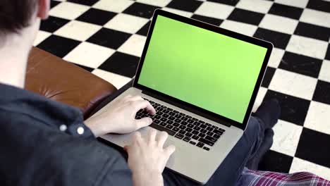 person working on laptop with green screen