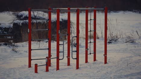 outdoor gym with no people at snowed park in winter, red metal fitness equipment empty in the snow, athletic urban lifestyle