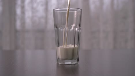 pouring cow milk into tall glass in slow motion, straight ahead shot