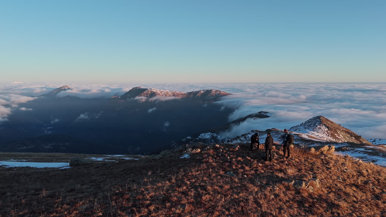Hikers explore mountain summit surrounded by breathtaking clouds at sunrise