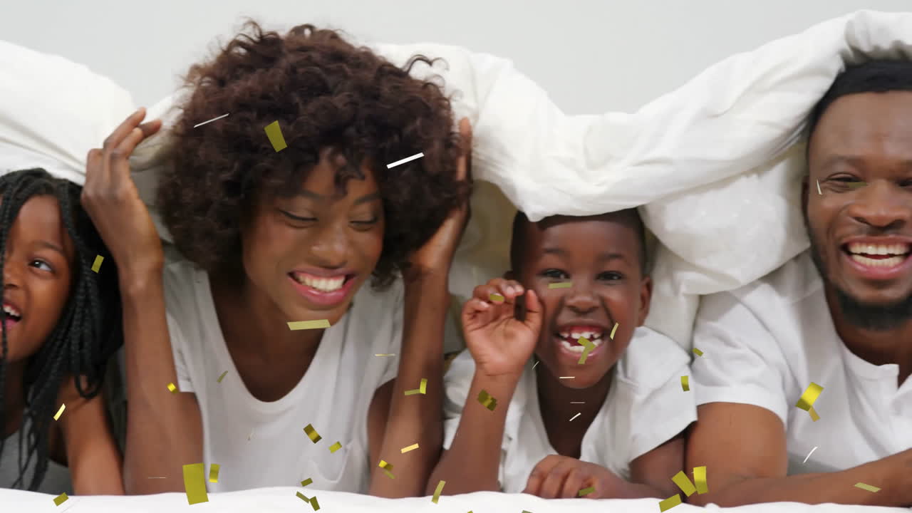 играть под одеялом с конфетами, счастливая семья наслаждается временем вместе.