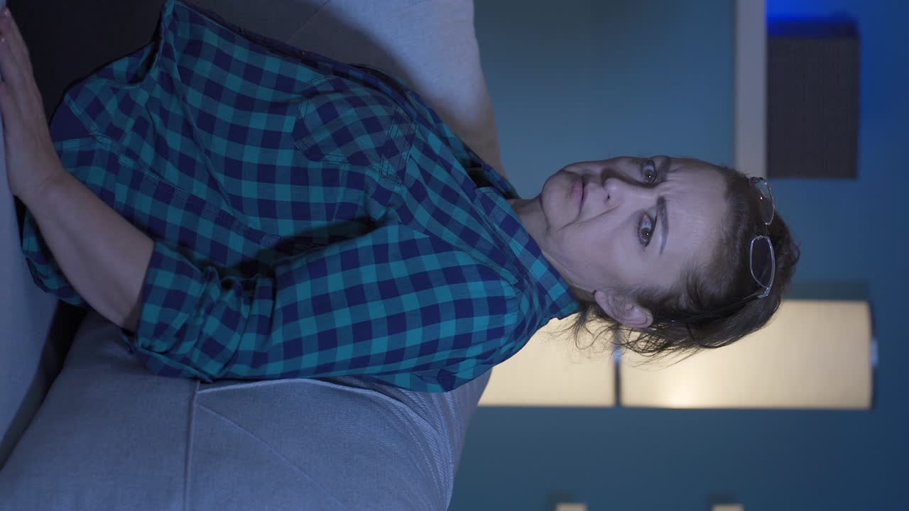 video vertical de una mujer sola por la noche en casa asustada y mirando a su alrededor.