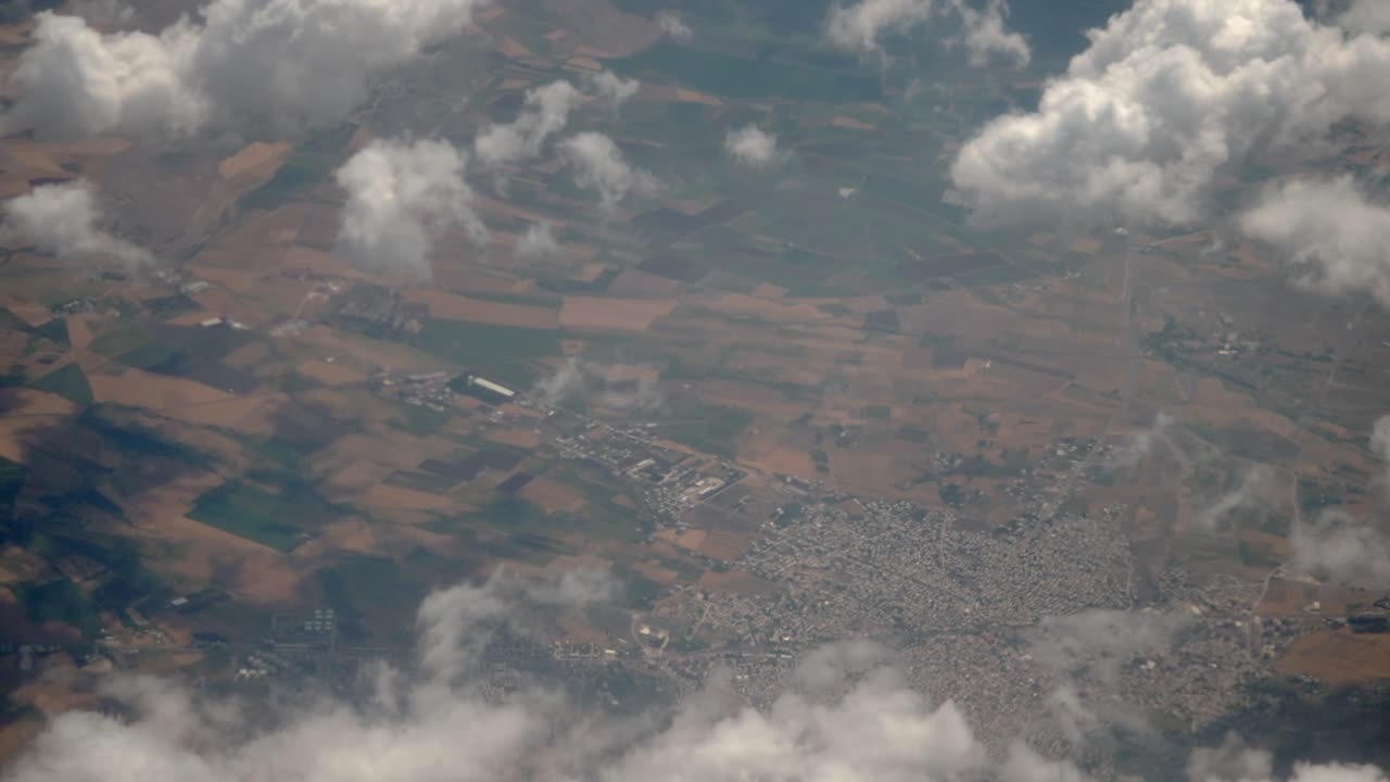 Aerial view of a landscape with clouds, agricultural fields, and a town