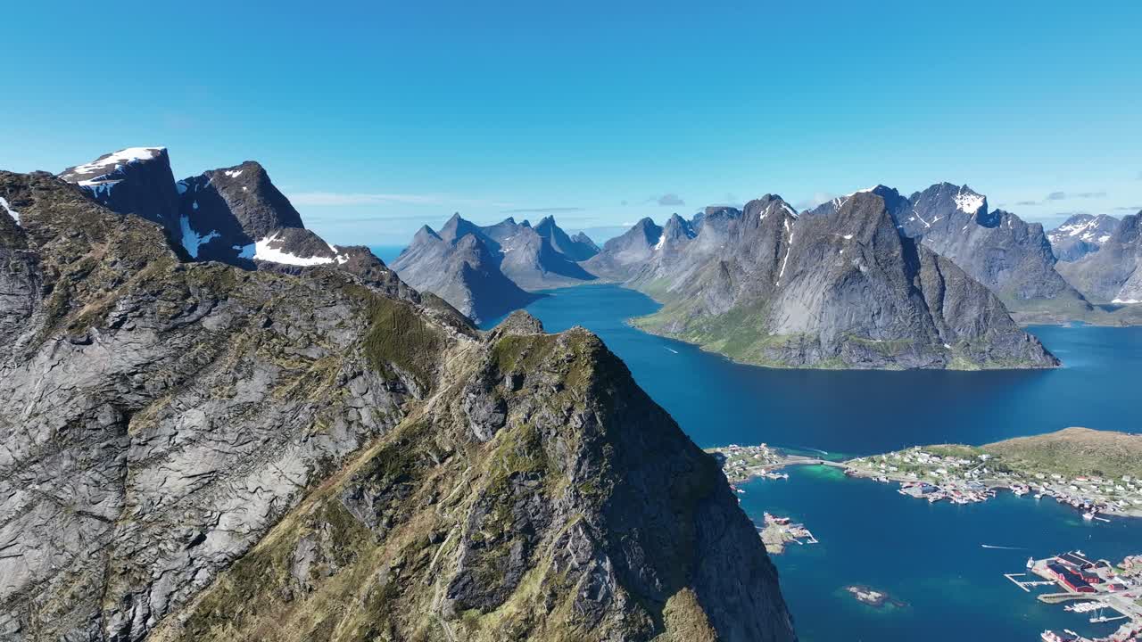 Orbiting Reinebringen cliff with Kjerkfjorden peaks parallaxing behind and Reine village below