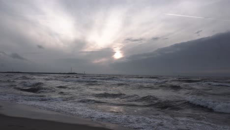 Zoom-in-shot-of-wind-ocean-waves-and-cloudy-dark-sky-during-yellow-sunset-in-Baltic-sea-at-the-evening