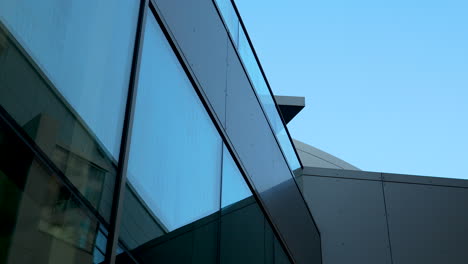 modern architectural detail with angled glass facade against sky