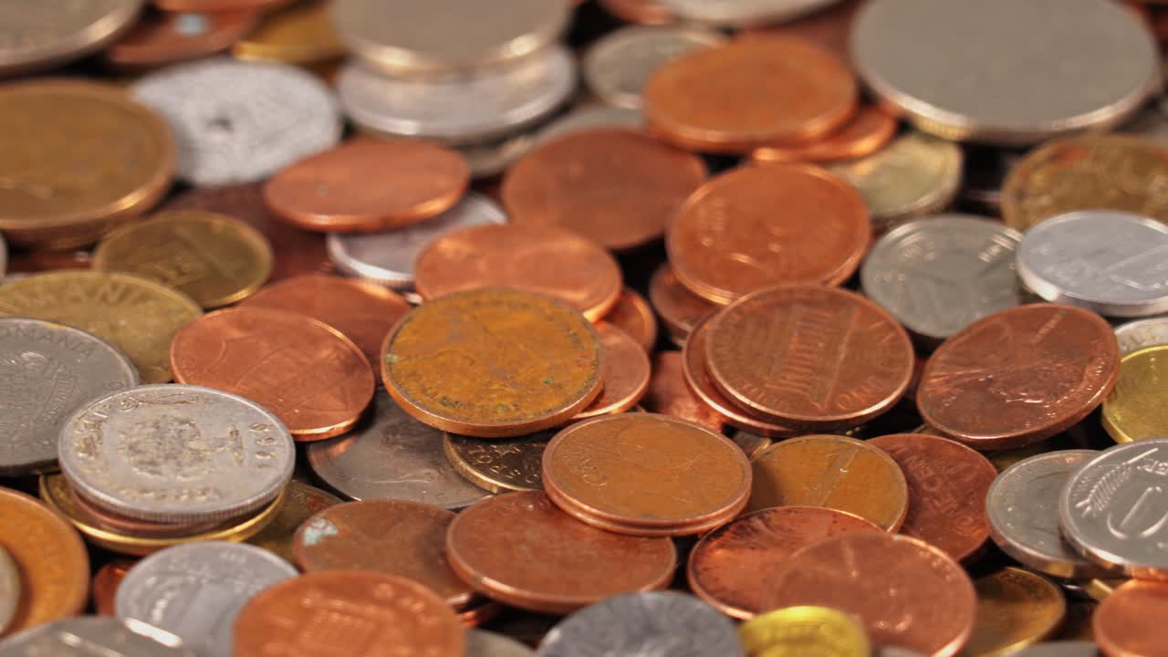 Coins of different sizes and colors scattered on a flat surface