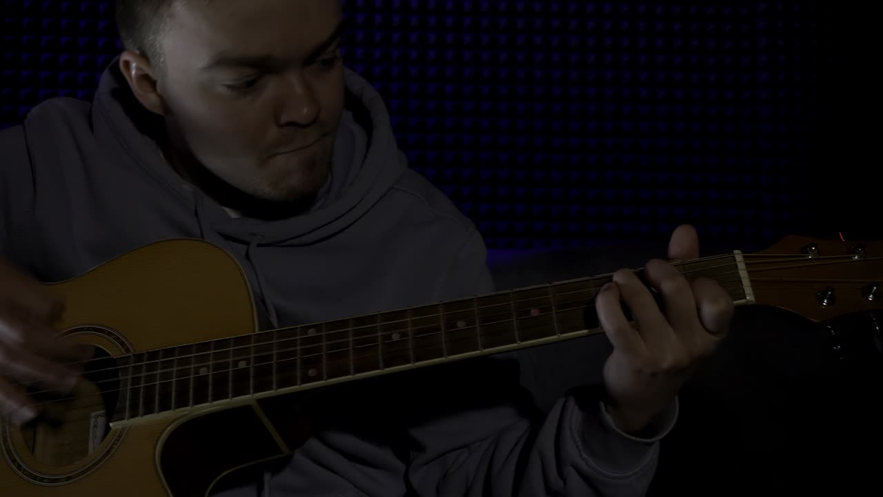 человек играет на акустической гитаре в студии звукозаписи