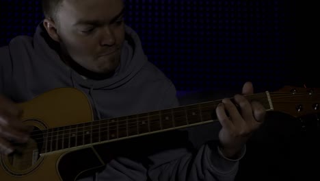hombre tocando la guitarra acústica en un estudio de grabación