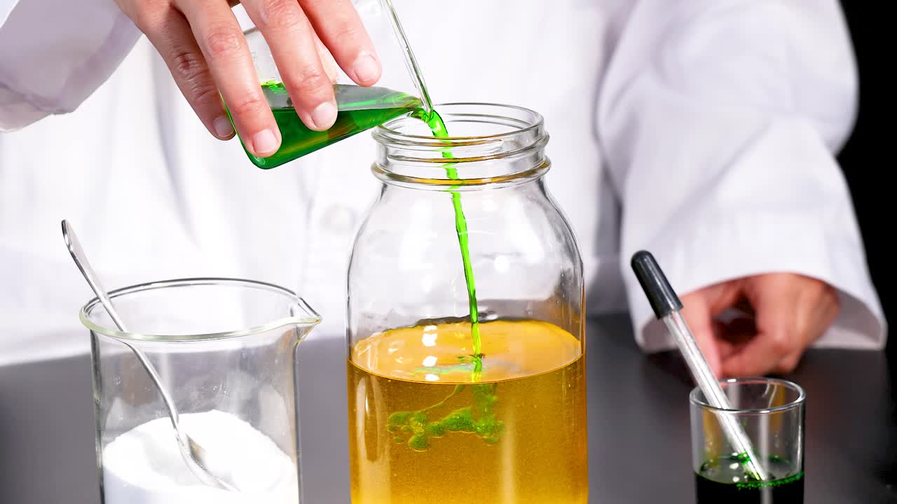 A scientist pours green liquid into a jar, creating a vibrant chemical reaction in a laboratory setting