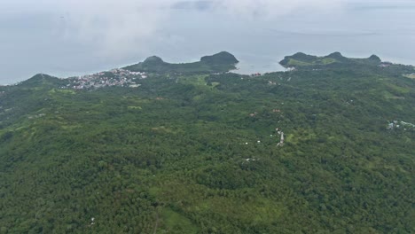 Vista-Emocionante-En-Un-Vuelo-Aéreo-Brumoso-Hacia-La-Costa,-El-Amplio-Bosque-Verde-Y-El-Océano-En-Calma