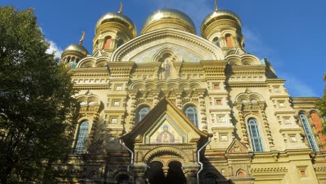 view of orthodox st nicholas naval cathedral golden domes and crosses on blue sky in sunny autumn day at karosta, liepaja, tilt up wide shot