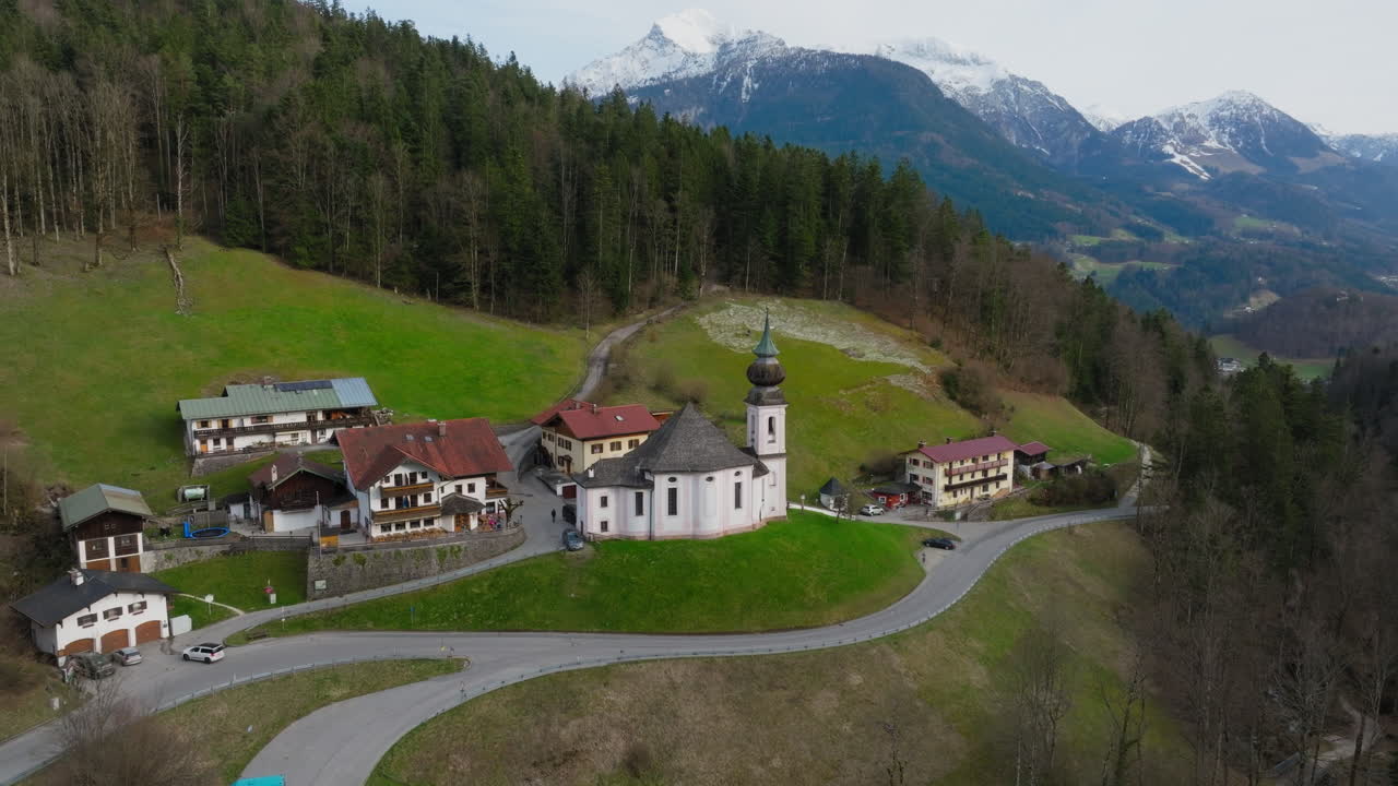 Maria Gern Church in Berchtesgaden, Bavaria, Germany, historic alpine church under cloudy skies, aerial descend and tilt down approach