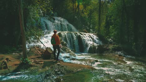 young modern man hiking at natural majestic waterfall at krka national park in croatia with its exceptional lush green beauty in spring time. cinemagraph / seamless video loop of the famous tourist vacation and filming location of karl may winnetou movies