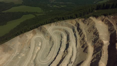 Epische-Drohnenaufnahme-Eines-Muldenkippers,-Der-Mitten-In-Der-Sonne-Durch-Eine-Steinbruch-Baustelle-Fährt