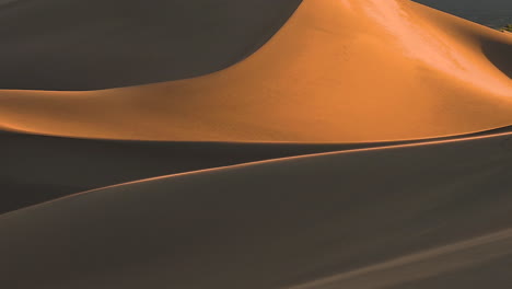 wind blowing the top of sand dunes in the desert, sunrise make beautiful light and shadow on sand dunes mountains