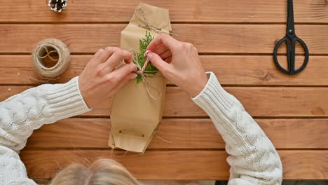 Las-Manos-Femeninas-Usan-Una-Pistola-De-Pegamento-Para-Decorar-Un-Regalo-Envuelto-Con-Decoraciones-En-Una-Mesa-De-Madera