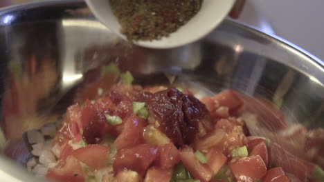 slow motion macro shot as seasoning, pouring condiments over vegetables in a bowl, tomatoes, onions and vegan gluten free food