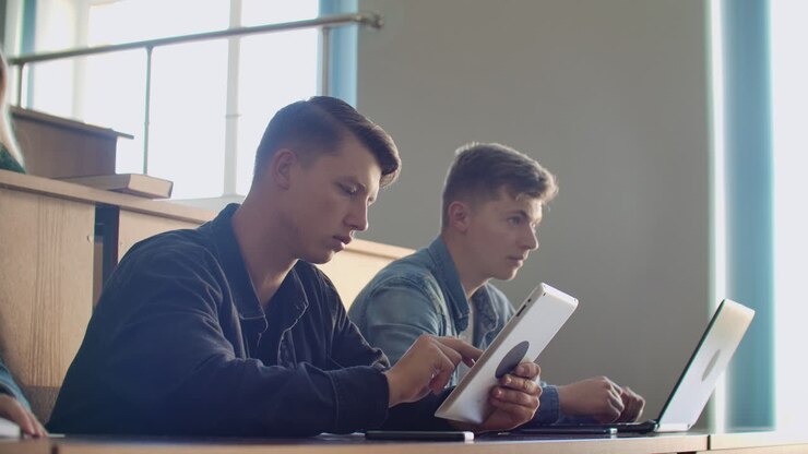 Large Group of Multi Ethnic Students Working on the Laptops while Listening to a Lecture in the Modern Classroom. Bright Young People Study at University.
