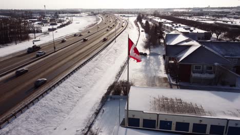 an aerial shot of a curved winter highway with the canadian flag in the foreground