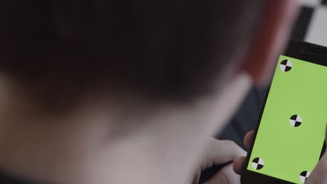 persona mirando un teléfono inteligente con una pantalla verde