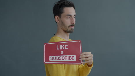 man holding a like and subscribe sign