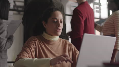 mixed-race woman using laptop in office