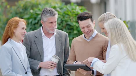 group of business professionals discussing ideas outdoors with a tablet