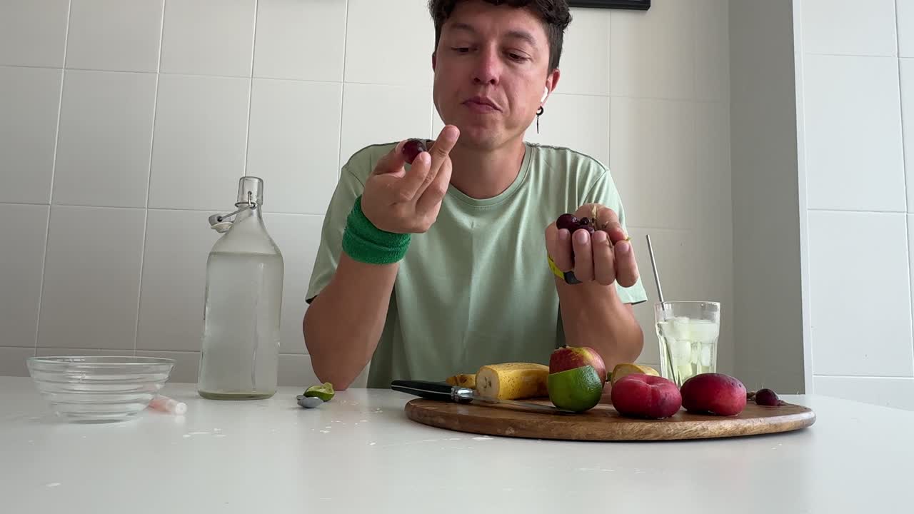Uomo che mangia frutta fresca e taglia una banana in cucina