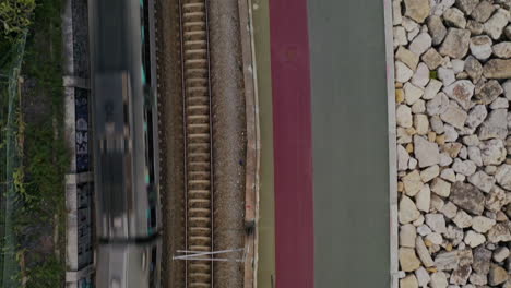 aerial shot top down view rail tracks with train passing by, portugal