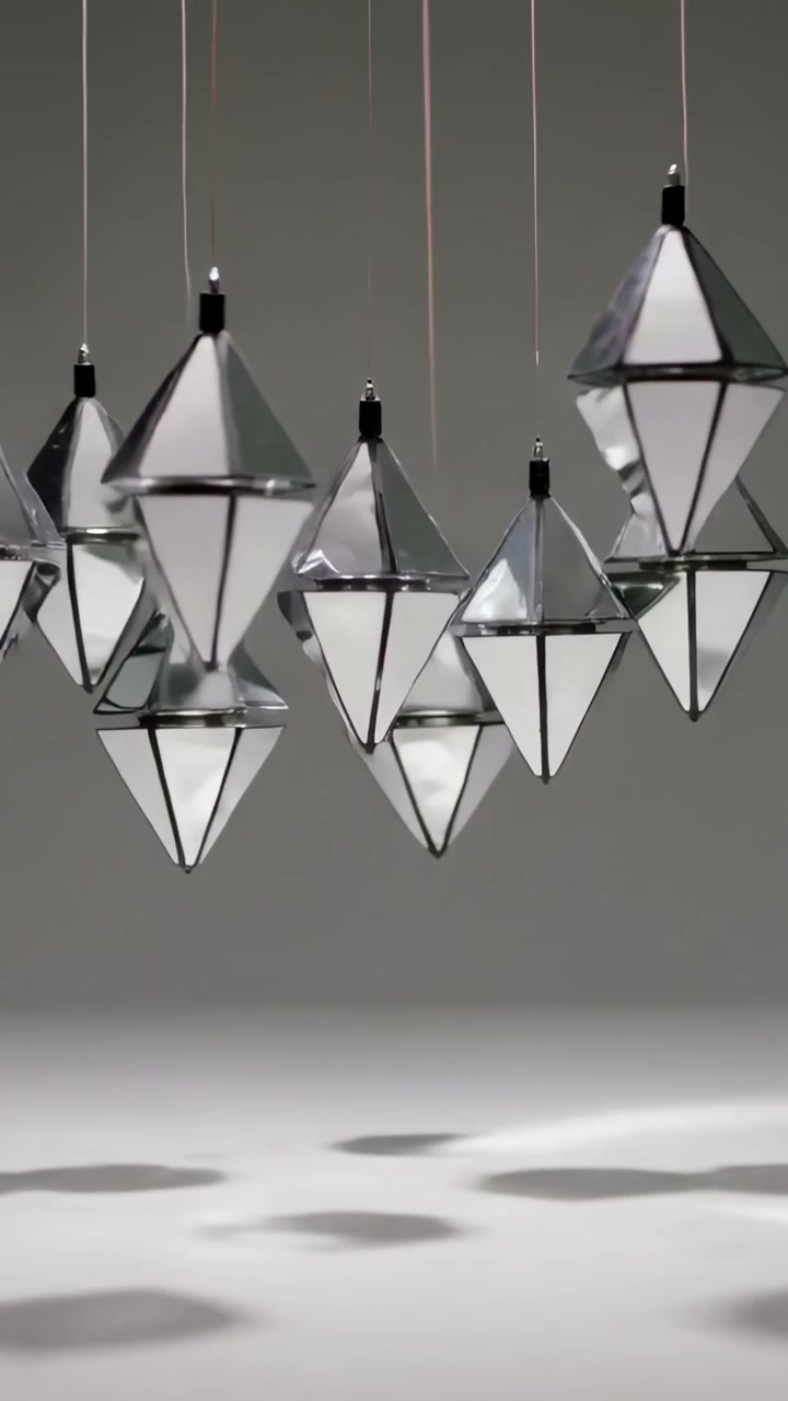 Vertical video: Pulling back camera showing pendants tilting and turning in studio, casting shadows