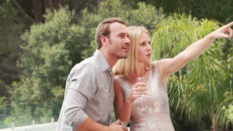 Smiling-couple-with-champagne-flute-pointing-away