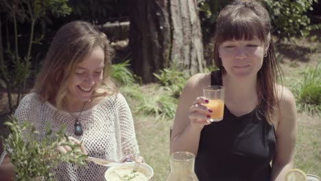 cheerful young woman eating and drinking in backyard