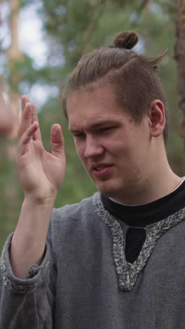 young man in forest in historical costume, waving off mosquitoes, subculture