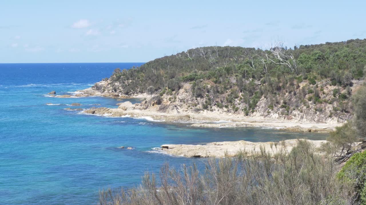 Paesaggio al rallentatore delle spiagge della baia oceanica con sentieri escursionistici lungo la costa rocciosa del promontorio, ricoperta da alberi e vegetazione arbustiva a Rosedale, costa meridionale del Nuovo Galles del Sud, Australia, viaggi nella natura e turismo