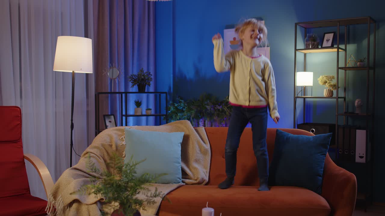 niña feliz niño bailando baile de moda mientras escucha música en casa sola de pie en el sofá