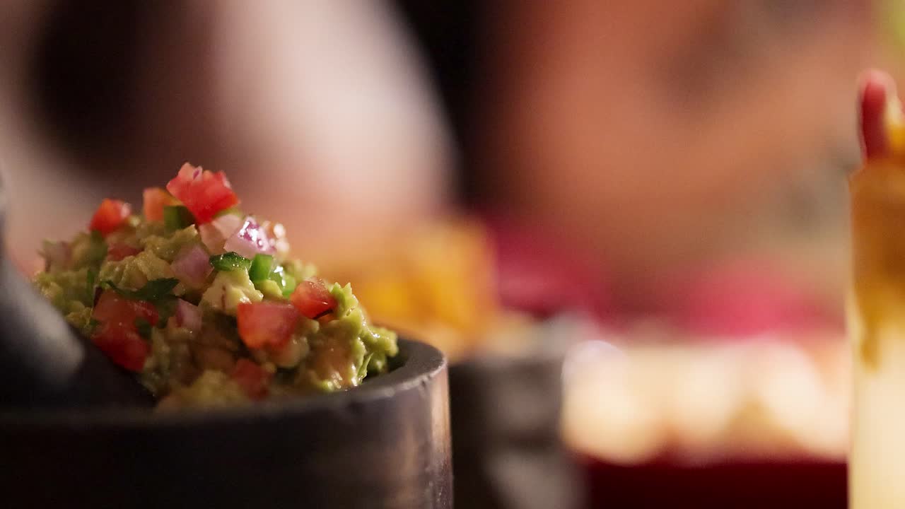 Close-up of guacamole in a lively restaurant environment with warm lighting and colorful decor