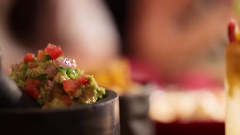 close-up of guacamole in a lively restaurant environment with warm lighting and colorful decor
