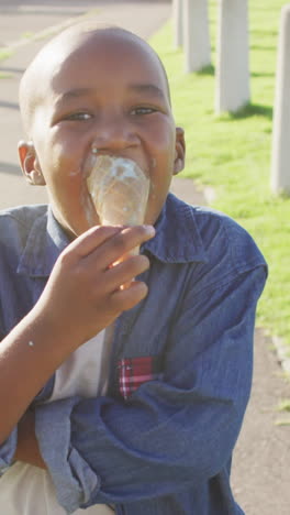 video de un niño afroamericano feliz comiendo helados en un día soleado
