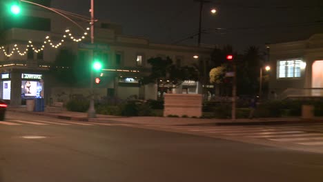 a car travels along a street at night in santa monica california as seen through the rear window at an angle 1