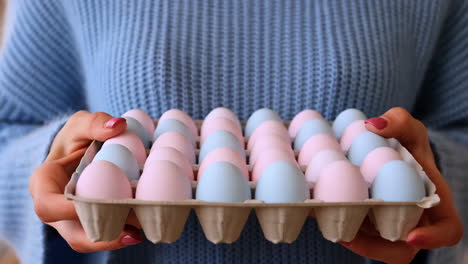 person holding a carton of pastel pink and blue easter eggs
