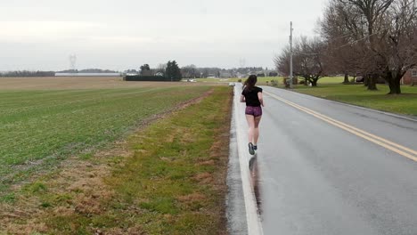 Low-tracking-slow-motion-follow-shot-of-attractive-competitive-female-runner-training-for-race,-strength,-persistence,-grit,-intensity-theme,-girl-power