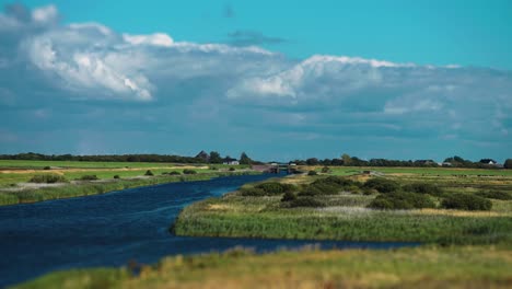 a channel cuts through the lush green valley in rural denmark