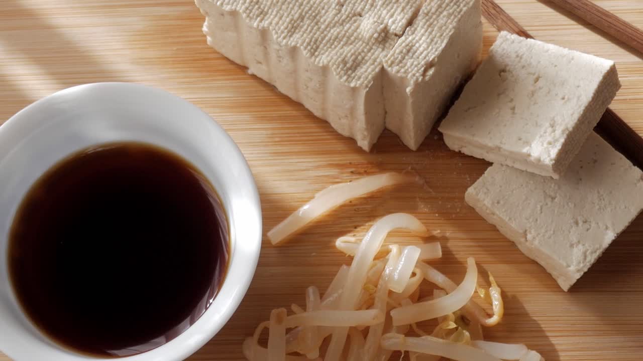 Tofu, soy sauce and bean sprouts on wood board in calm natural morning light