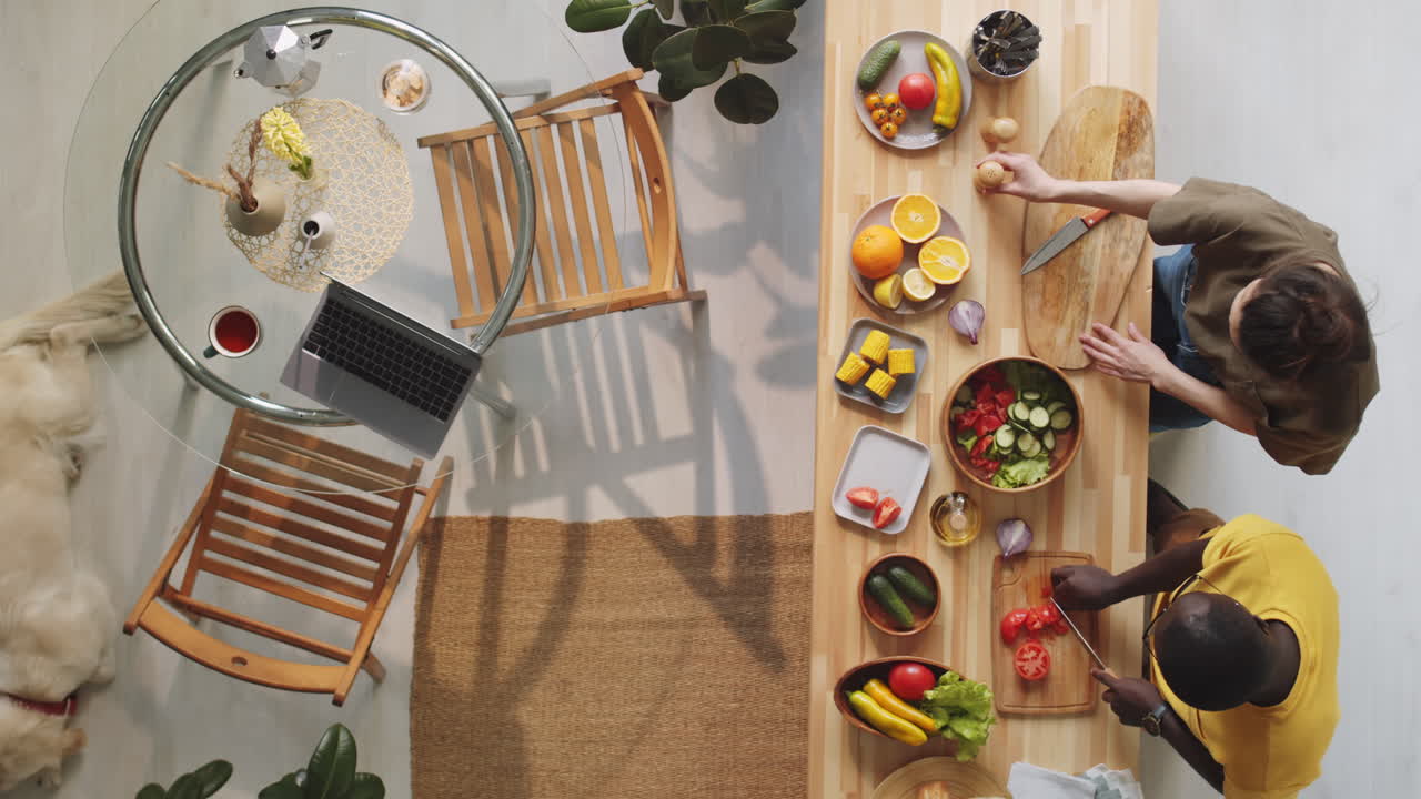 개 가 자고 있는 동안 다민족 부부 가 집 에서 음식 을 요리 하고 있다