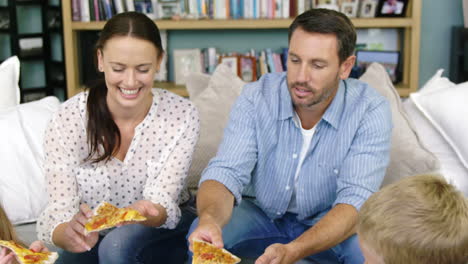 familia feliz comiendo pizza en un sofá juntos