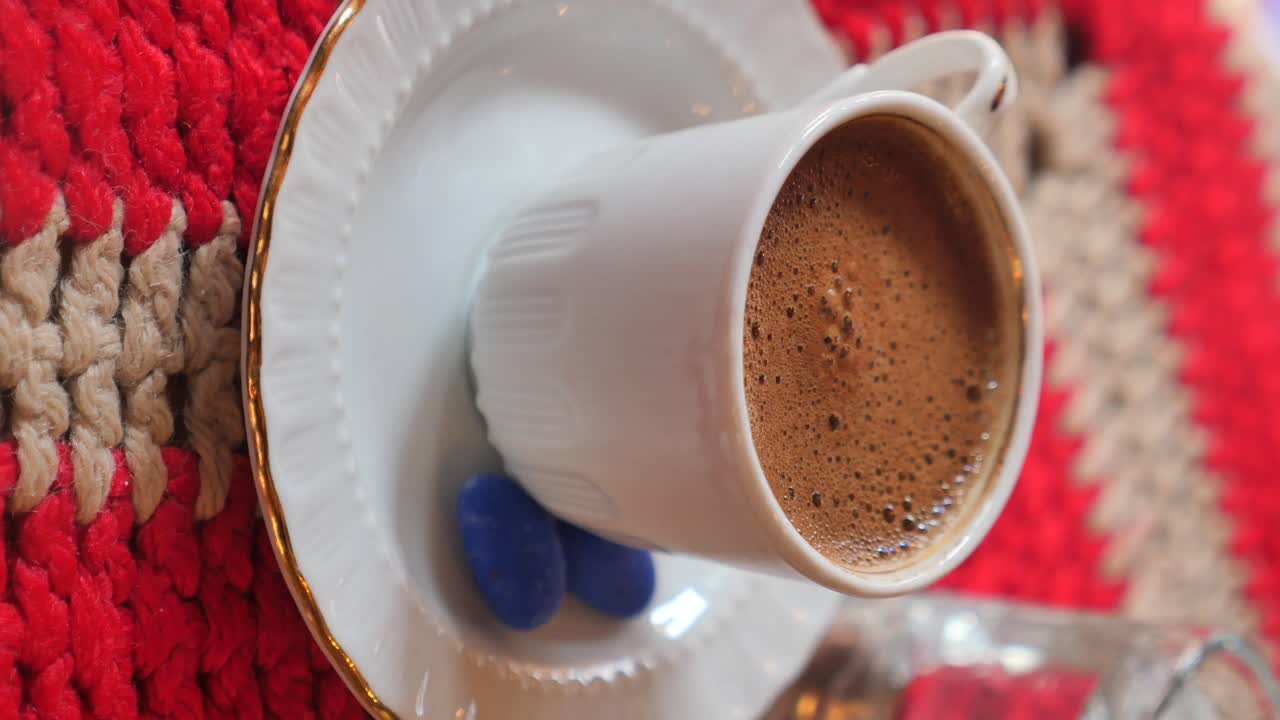 Close-up of Turkish Coffee in a White Cup with Blue Accents on a Patterned Background