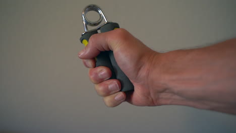 slow motion of a man working on his grip and forearm strength with a handgrip strengthener