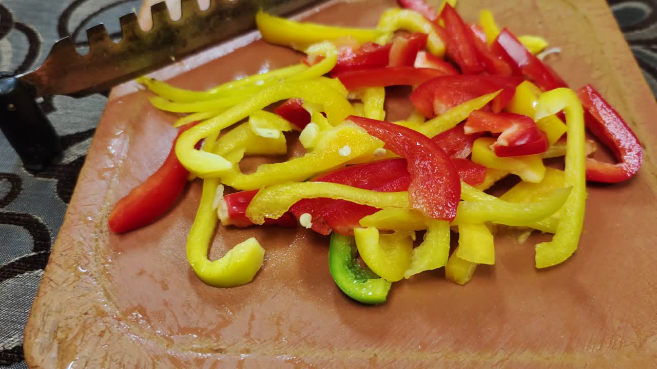 신선한 빨간색과 노란색 고추는 스테인리스 스 칼날로 갈색 채소 절단기에 어