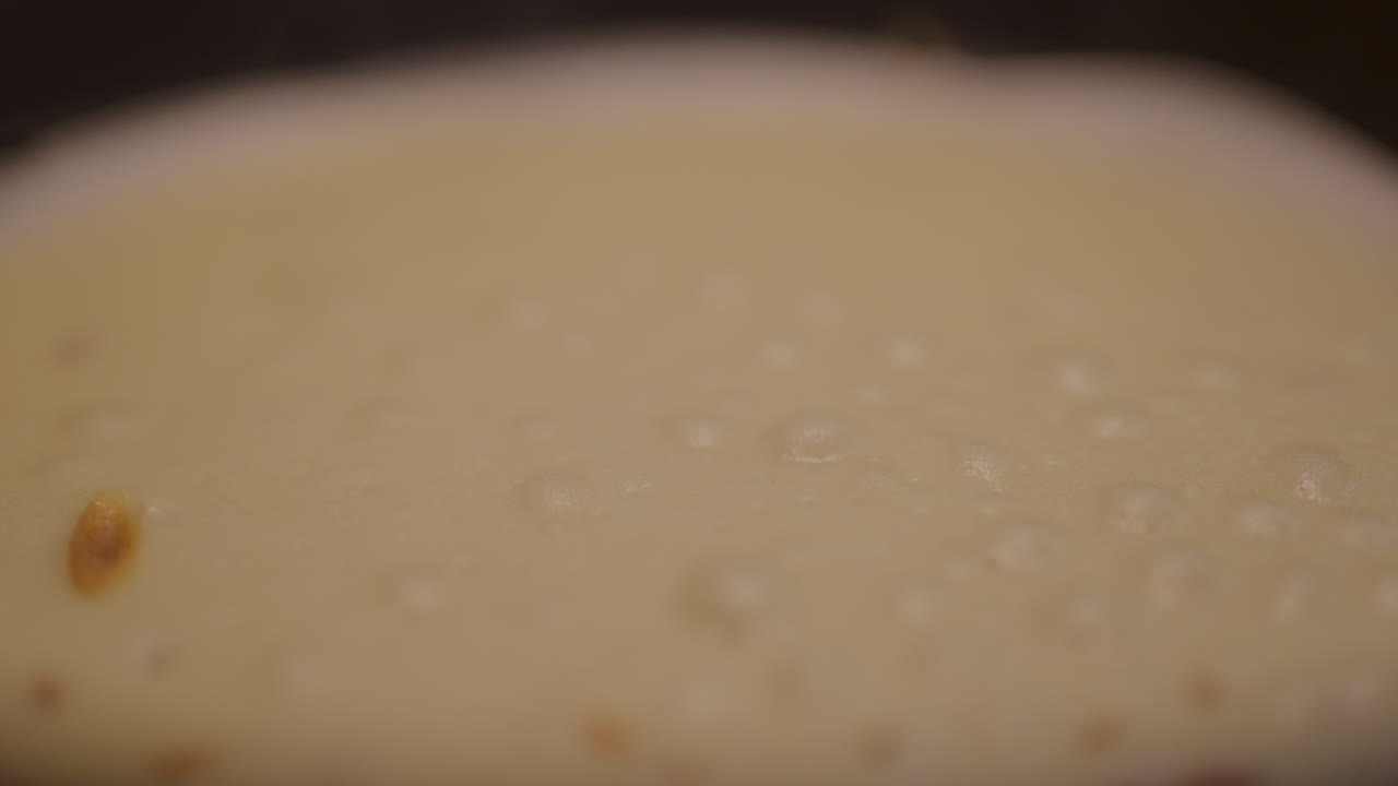 macro primer plano de las burbujas de aire en el panqueque mientras se frita